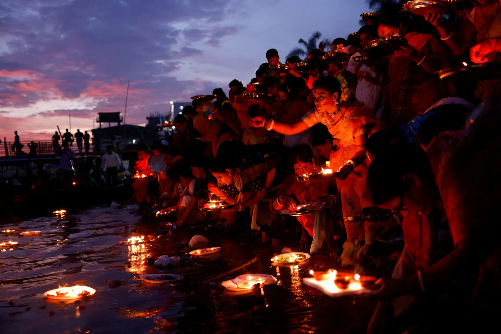 FÉ. Devotos hindus lançam lamparinas de óleo acesas nas águas do rio Buriganga, no Bangladesh