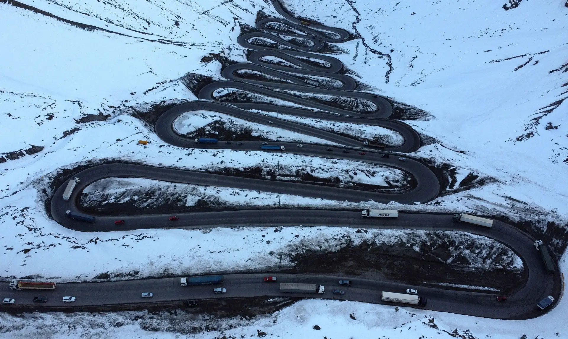 ALTITUDE. Uma serpente de trânsito desbrava caminho entre a neve, numa zona montanhosa entre o Chile e a Argentina