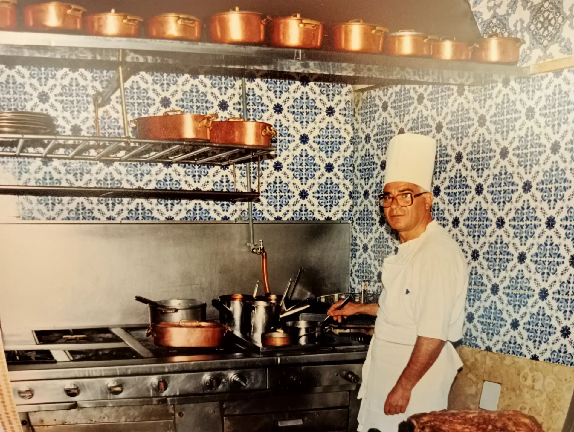 O chef Rocha na cozinha, ainda com azulejos na parede, tachos em cobre e o fogão feito à medida