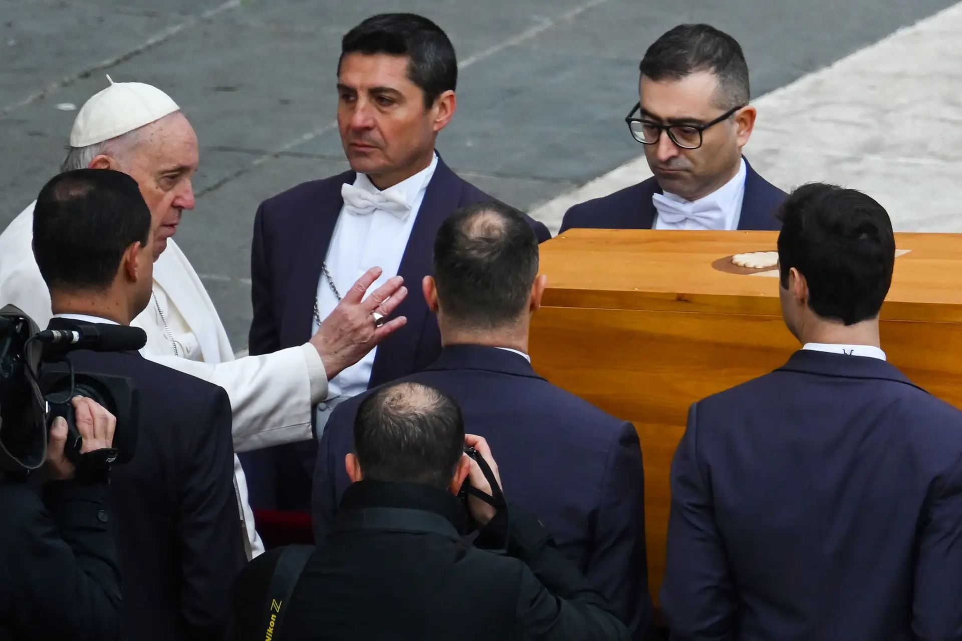 O Papa Francisco, que chegou de cadeira de rodas e se manteve sentado durante a maior parte das cerimónias, ergueu-se no final e prestou homenagem ao seu antecessor.