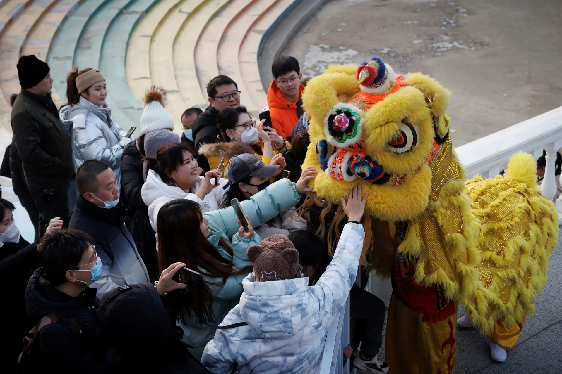 Pessoas tocam nos bailarinos disfarçados de dragão, numa apresentação do Festival da Primavera antes do Ano Novo Lunar Chinês no Parque Qinglong Hu em Pequim, na China