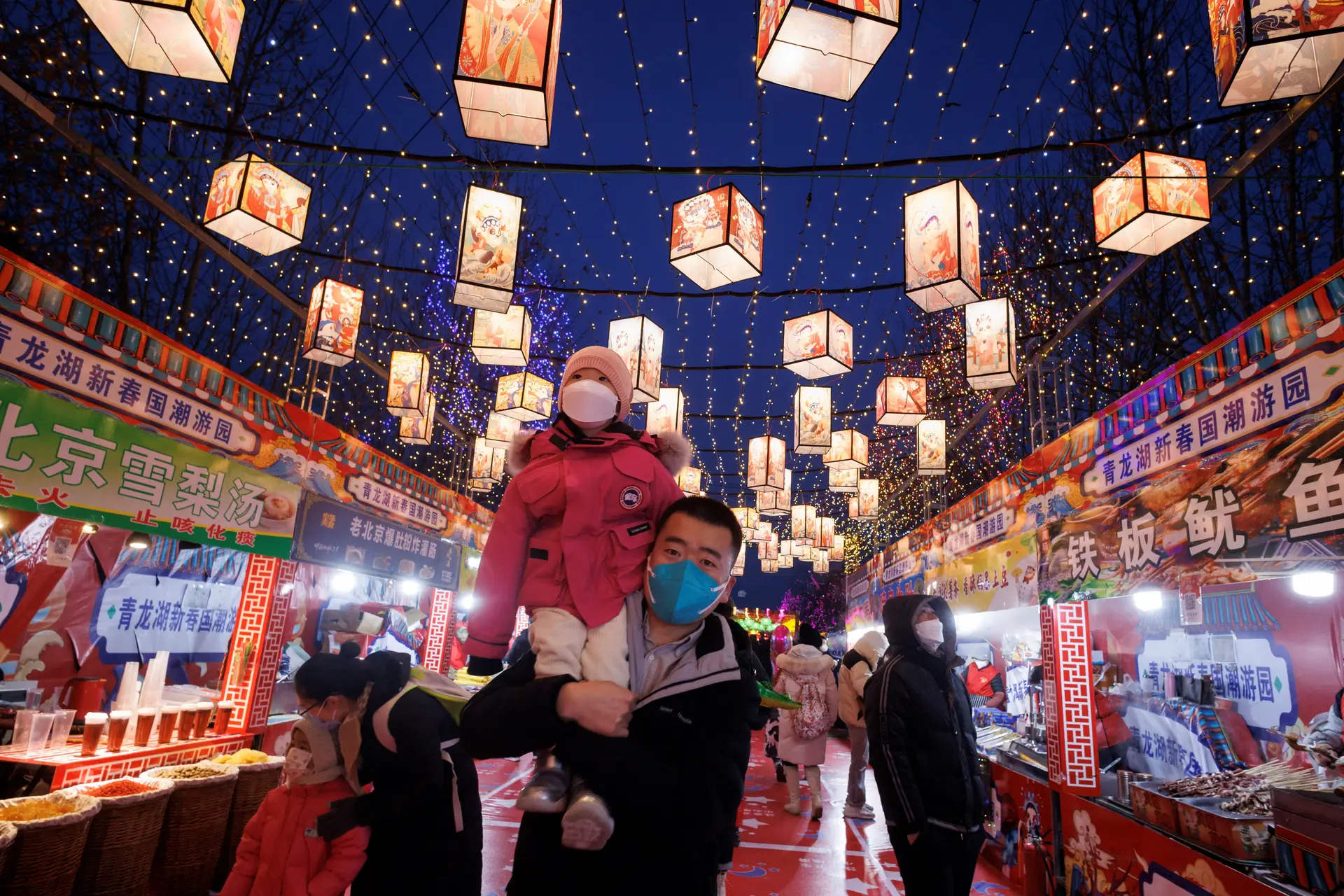 Pessoas caminham numa praça de alimentação decorada, parte de uma instalação de luzes do Festival da Primavera antes do Ano Novo Lunar Chinês no Parque Qinglong Hu em Pequim, na China