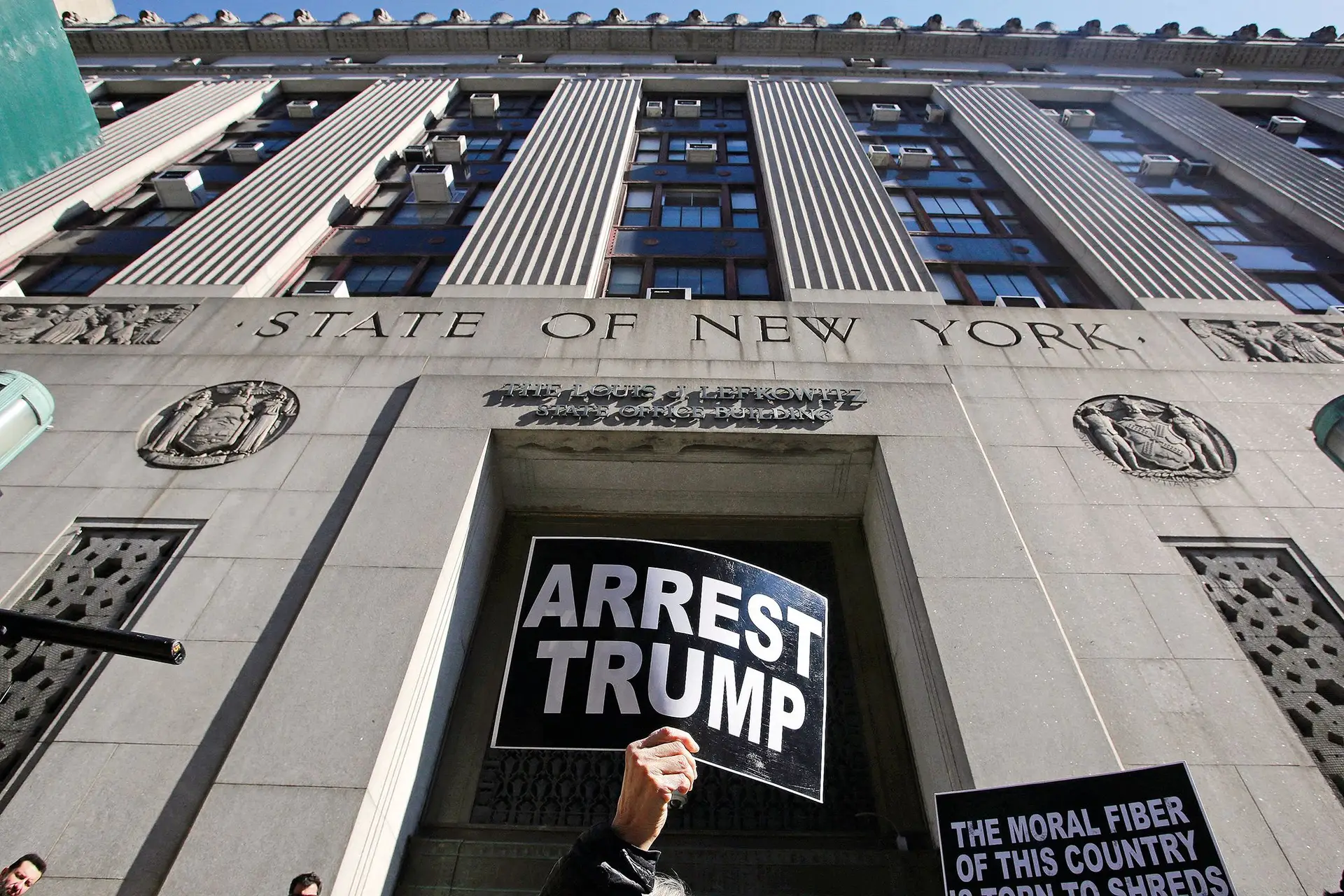 Protestos a exigir a detenção de Trump diante da procuradoria de Nova Iorque que investiga o suborno de uma atriz pornográfica para esconder o caso entre ambos