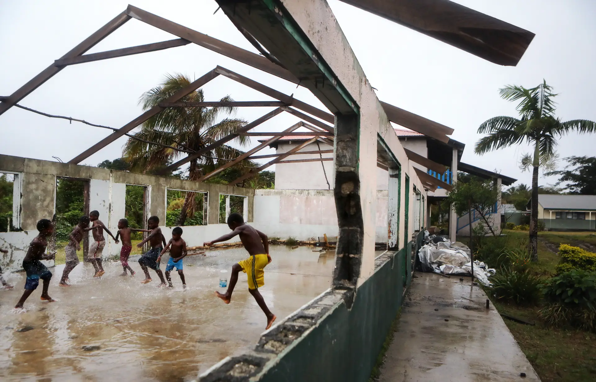 Crianças brincam à chuva no recreio de escola fortemente danificada Pam, que atingiu o Vanuatu em 2019