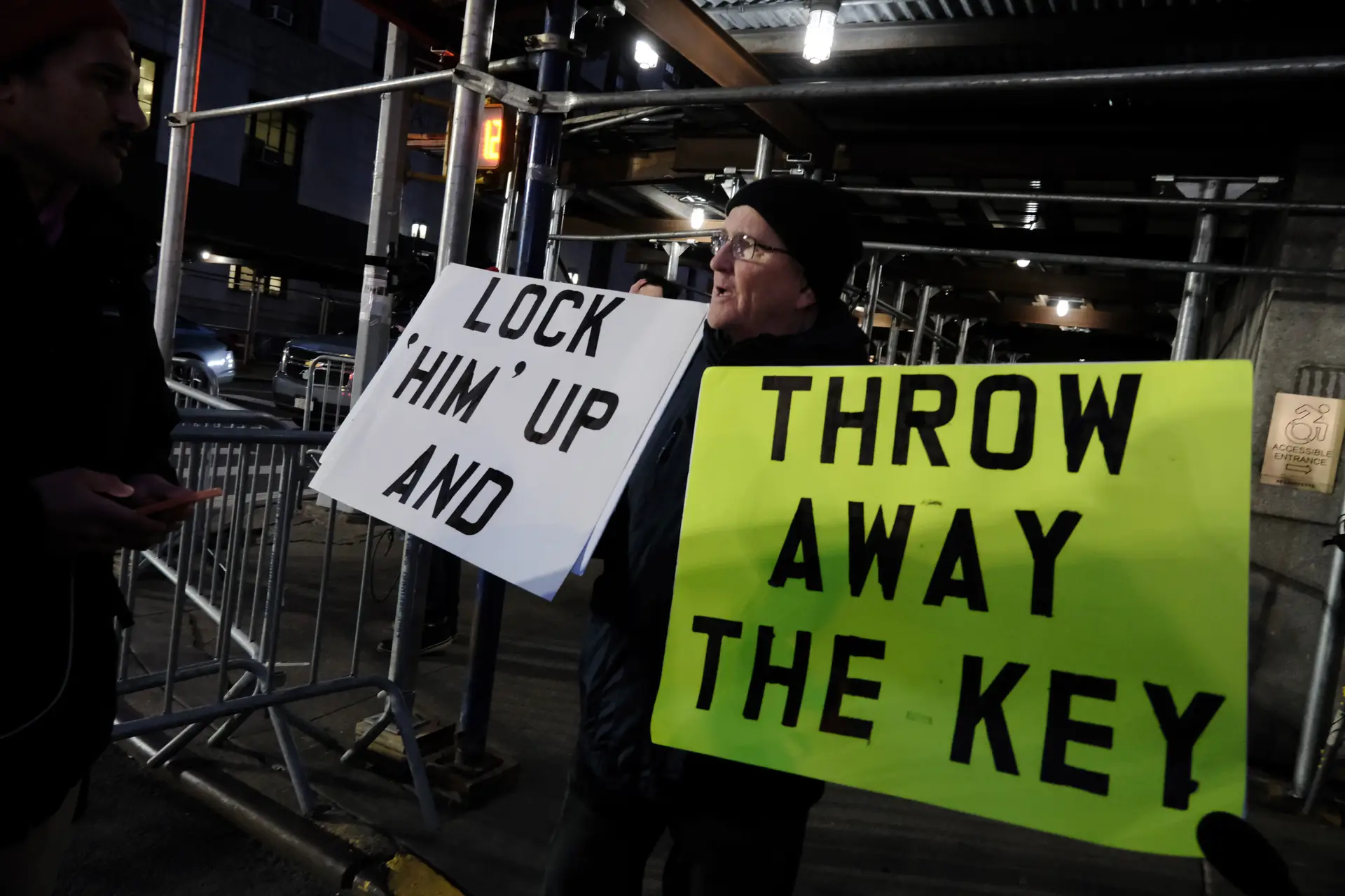 “Prendam-no e deitem fora a chave”, lê-se no cartaz. Manifestantes reuniram-se diante da procuradoria de Nova Iorque que vai acusar formalmente Donald Trump 