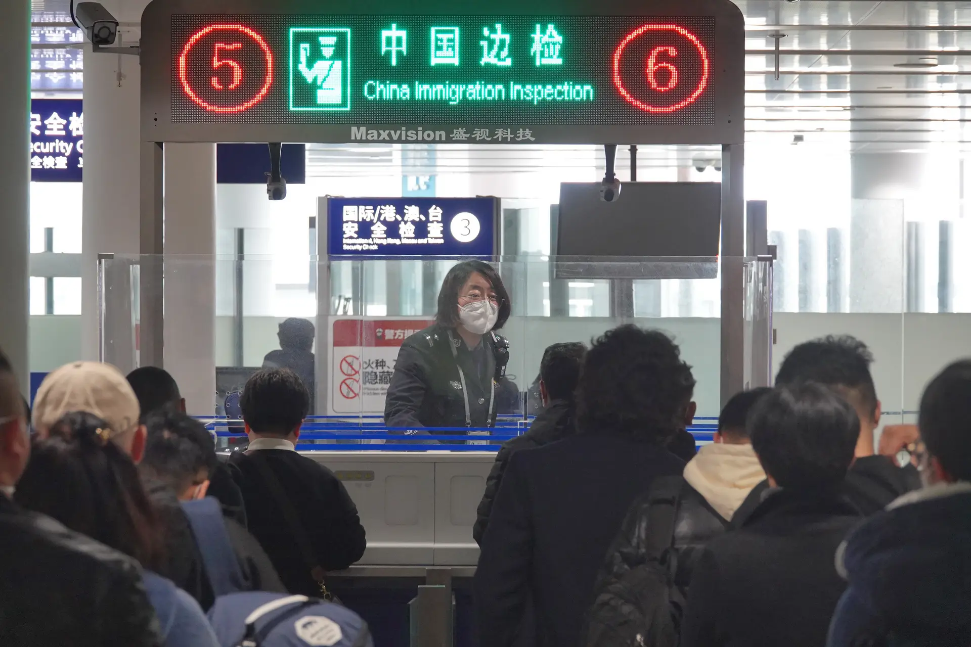 Guardas verificam os documentos de passageiros que saem da China pelo aeroporto de Yantai, na província de Shandong  