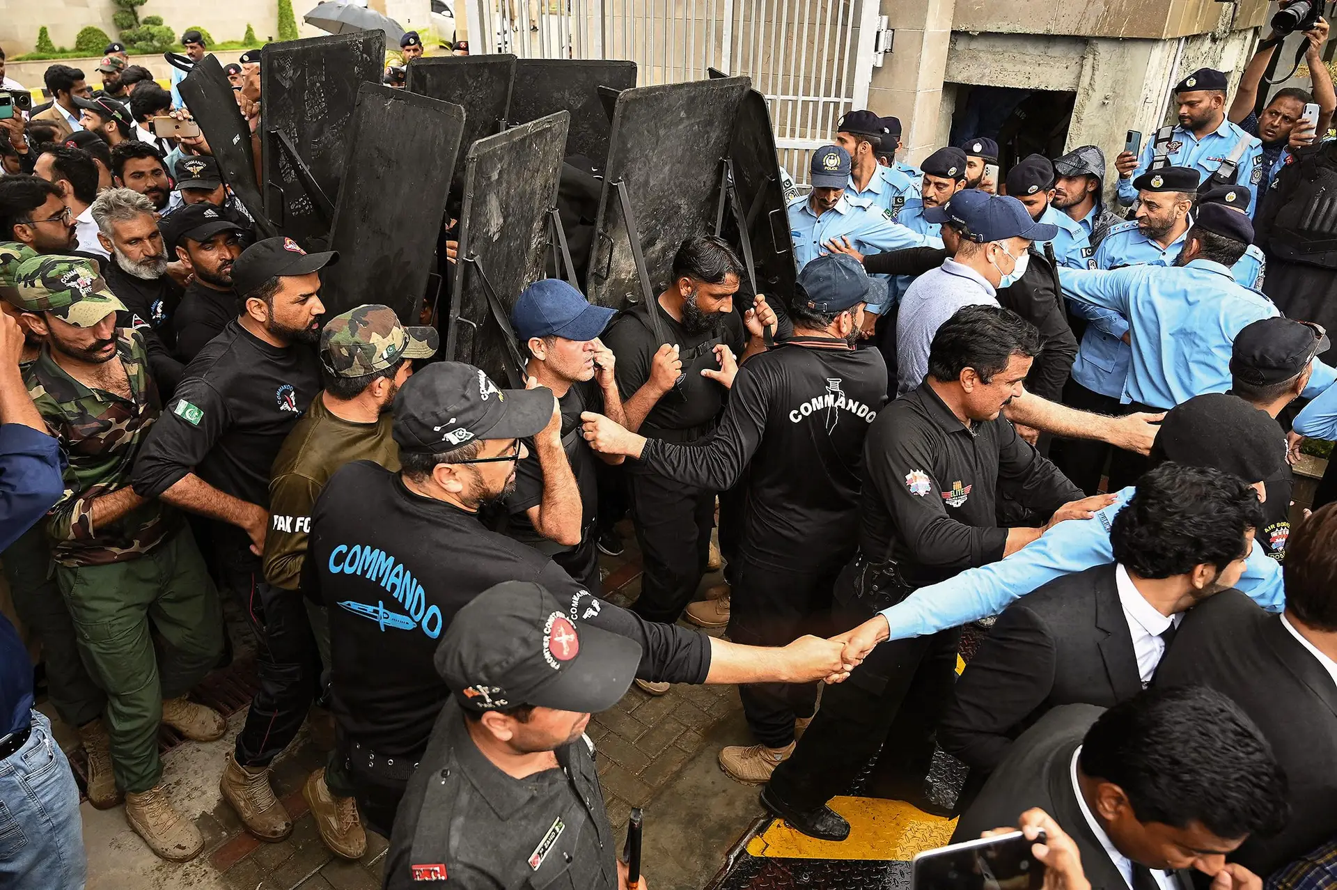 Forças de segurança escoltam Imran Khan (oculto) à saída de um tribunal de Islamabade