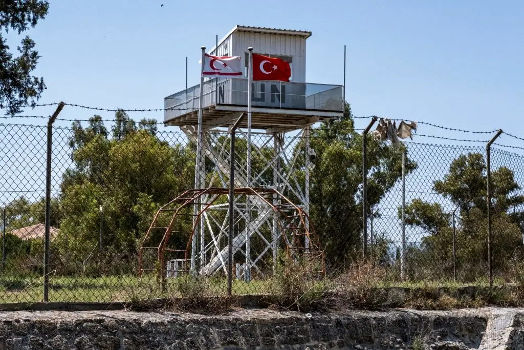 Bandeiras da Turquia e da República Turca de Chipre do Norte, junto a uma torre de vigia da ONU, em Nicósia