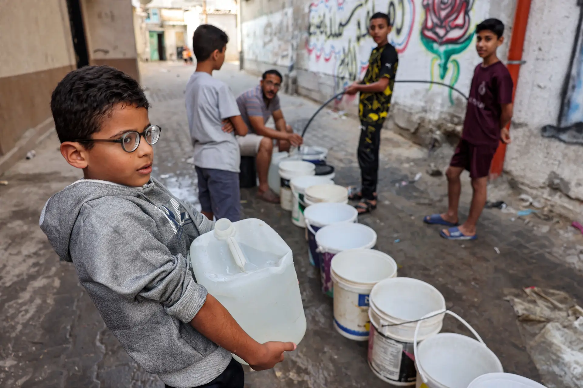 Crianças recolhem água em jerricãs em Rafah, no sul da Faixa de Gaza  