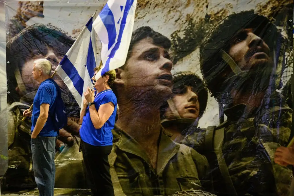 A reforma judicial levou às ruas, no ano passado, milhares de israelitas, como este casal em Telavive, a 30 de setembro, junto a uma imagem icónica da história de Israel