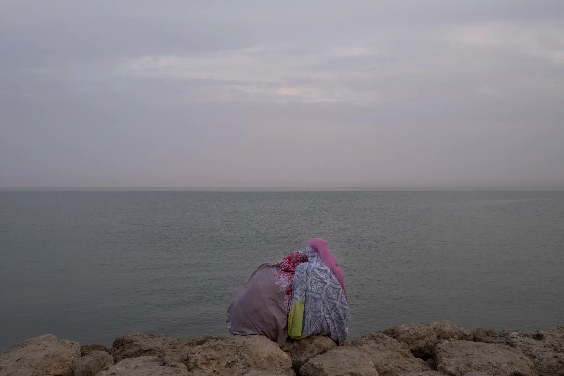 Duas mulheres sarauís sentadas, contemplam a baía da cidade de Dakhla. Ao fundo, vê-se a costa do Saara Ocidental.