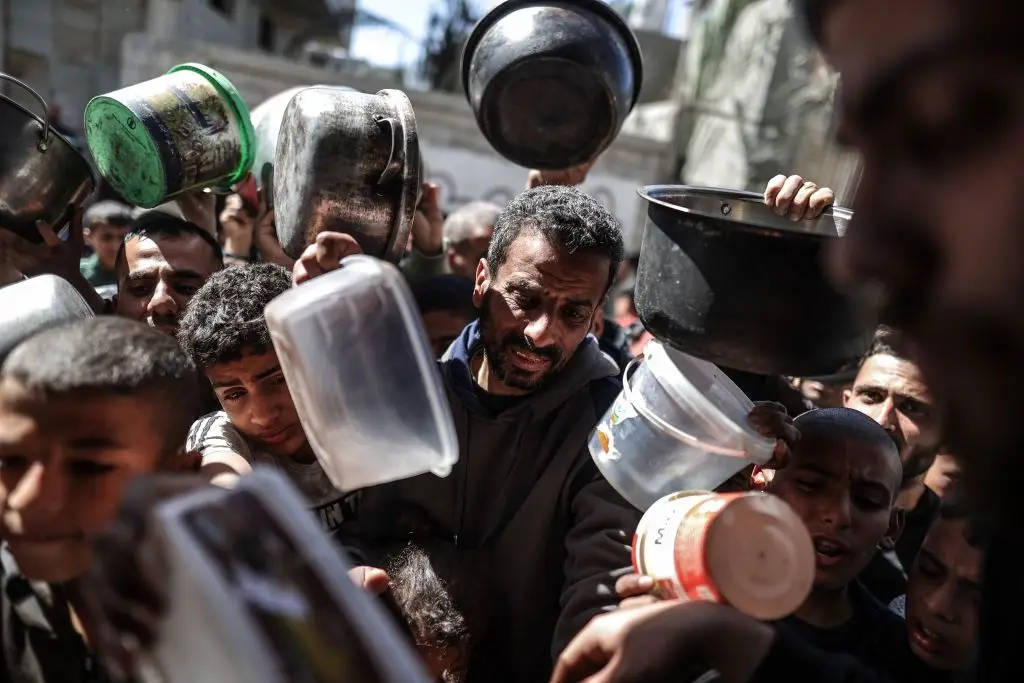 Palestinianos atropelam-se para tentar receber comida, em Deir al-Balah, na Faixa de Gaza