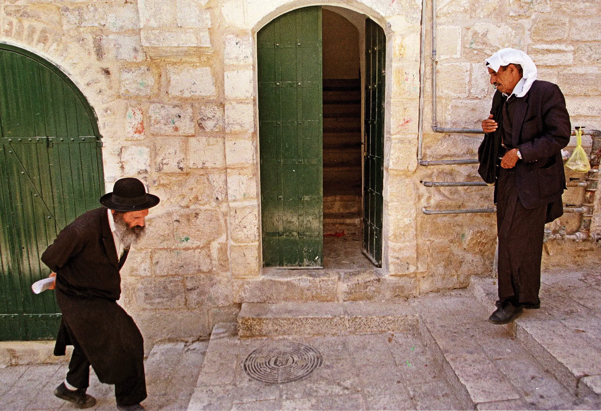 Um judeu ortodoxo e um palestiniano cruzam-se numa rua da cidade velha de Jerusalém, cidade sagrada para ambos