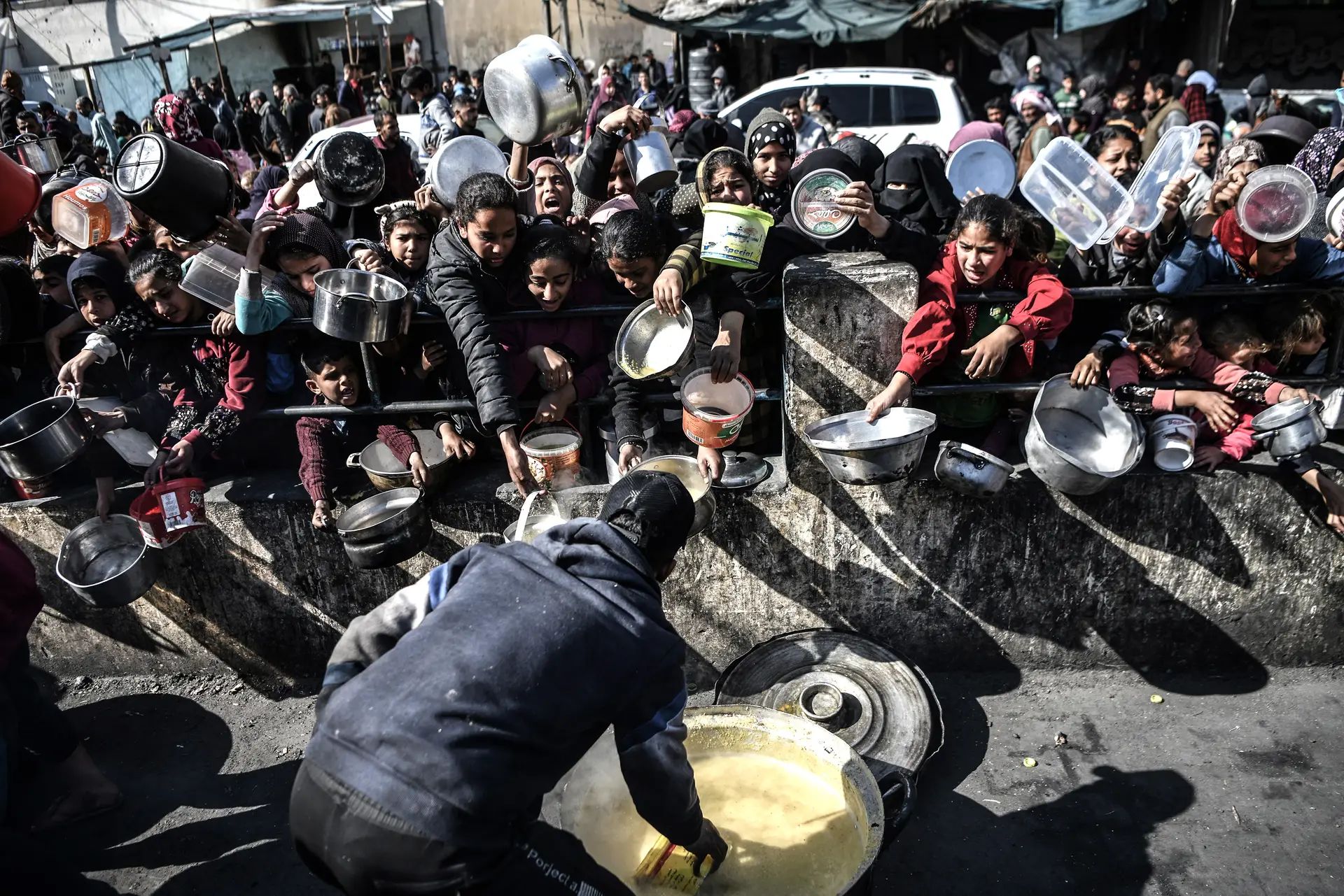 Civis palestinianos aguardam comida distribuída por organizações não governamentais na cidade de Rafah, no sul, perto da fronteira com o Egito