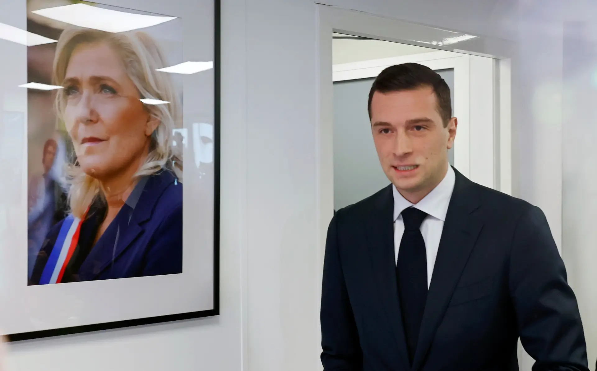 Jordan Bardella, candidato do Reagrupamento Nacional, ao lado do retrato da presidente do partido, Marine Le Pen