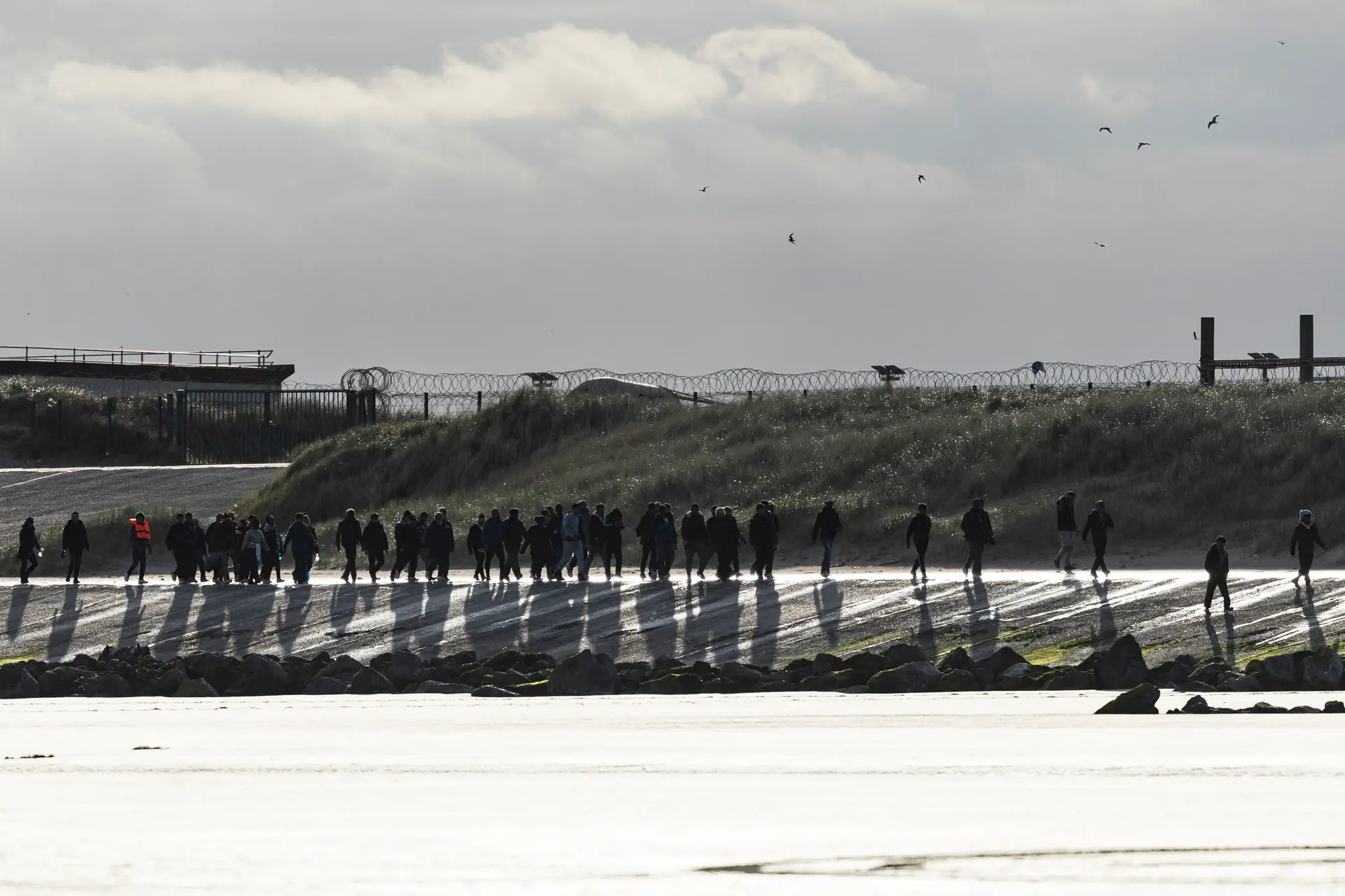 Migrantes atravessam uma praia, no norte de França, para chegar a um barco de contrabandistas, numa tentativa de atravessar o Canal da Mancha.