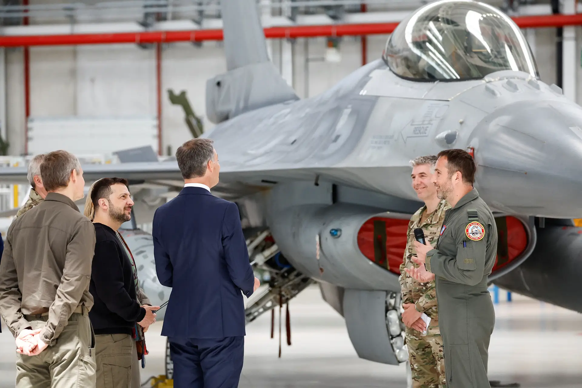O Presidente ucraniano, Volodymyr Zelensky, com o primeiro-ministro belga, Alexander De Croo, junto de um caça F-16, a 28 de maio de 2024, dia em que se encontraram com instrutores de treino na base aérea de Melsbroek, na Bélgica