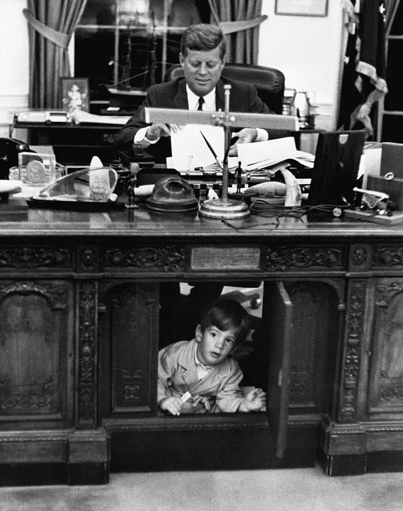 Enquanto JFK trabalha, John Kennedy Jr. brinca às escondidas, na Sala Oval da Casa Branca