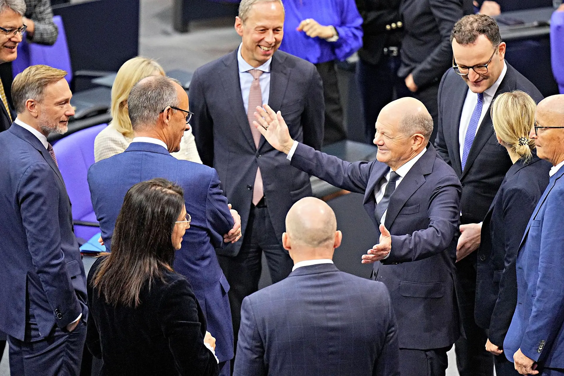 O chanceler Olaf Scholz (de braços abertos) no Parlamento, com o seu opositor Friedrich Merz (de costas) e o ex-aliado Christian Lindner (à esquerda)