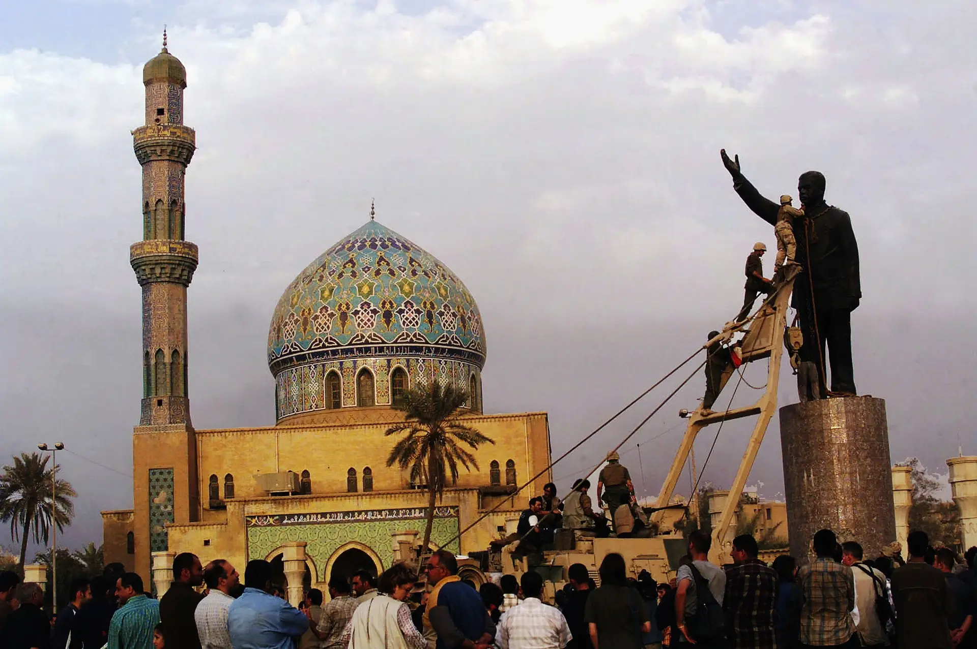 Militares americanos sobem ao topo de uma estátua de Saddam Hussein para derrubá-la, a 9 de abril de 2003, em Bagdade