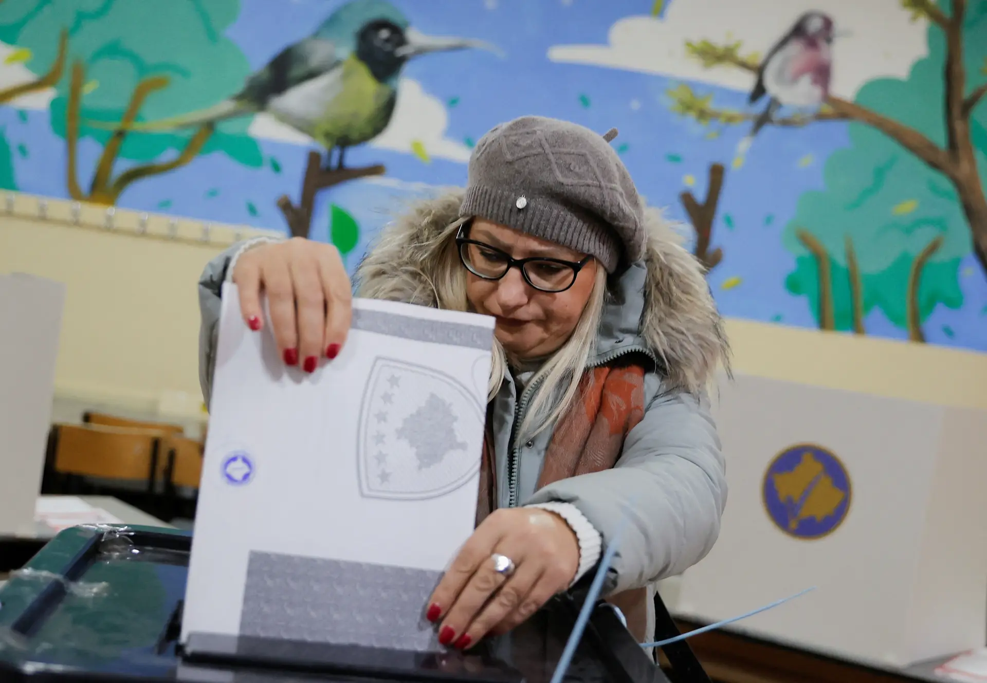 Eleitora deposita o boletim de voto nas eleições legislativas do Kosovo, em fevereiro de 2025