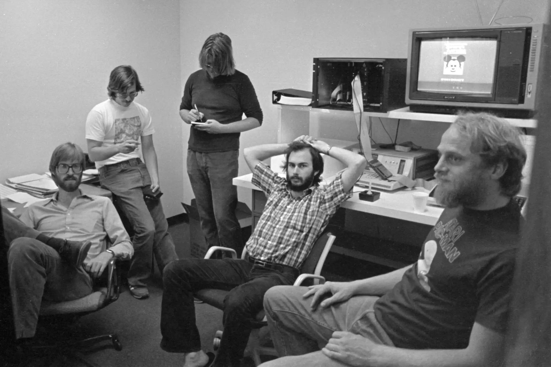 Howard Scott Warshaw, ao centro, sentado com as mãos na cabeça, numa reunião com mais profissionais da Atari