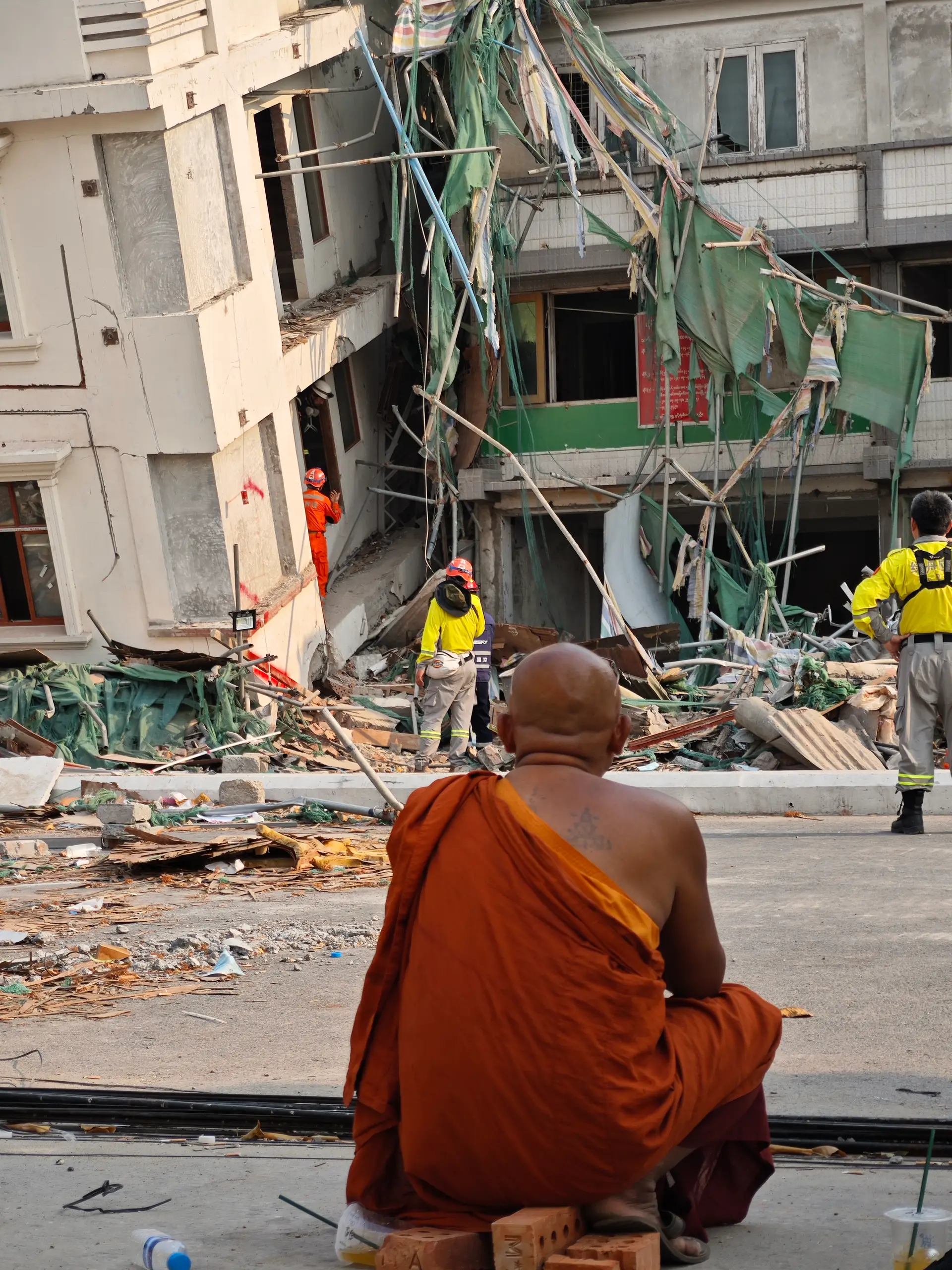 Um monge budista observa equipas de salvamento chinesas em Mandalay seis dias após o sismo que abalou Myanmar