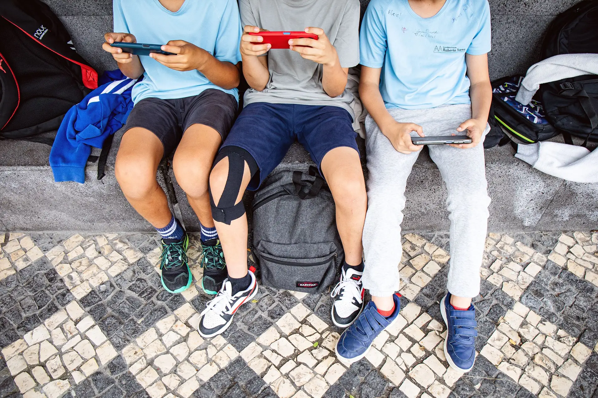 Crianças no recreio a usar telemóvel. O Ministério da Educação vai proibir smartphones no 1.º e 2.º ciclos a partir de setembro