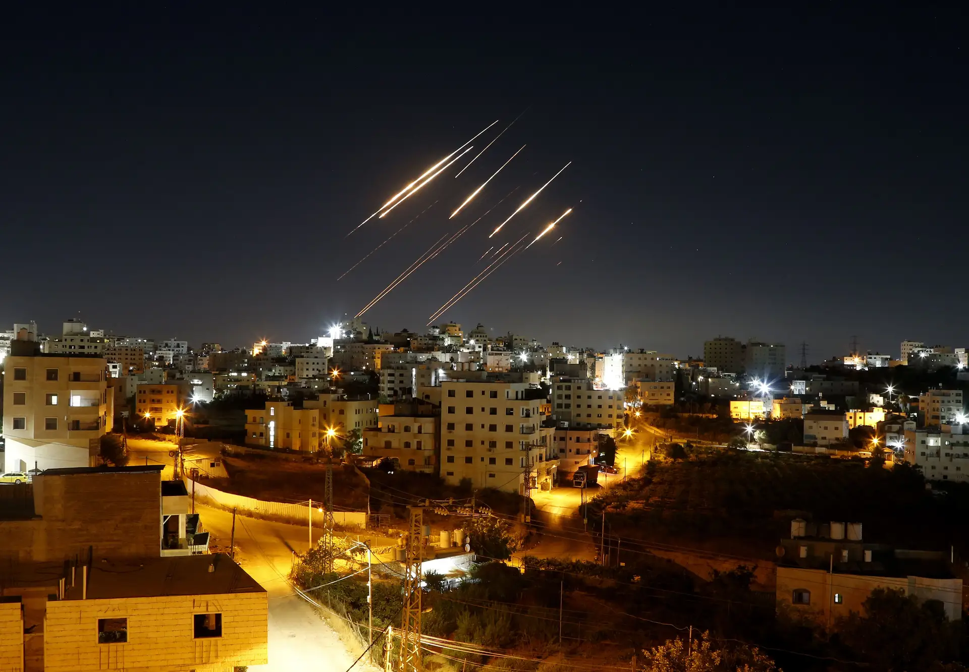 Feixes de luz de mísseis balísticos iranianos são vistos no céu noturno sobre Hebron, na Cisjordânia, num ataque de retaliação contra Israel, a 15 de junho