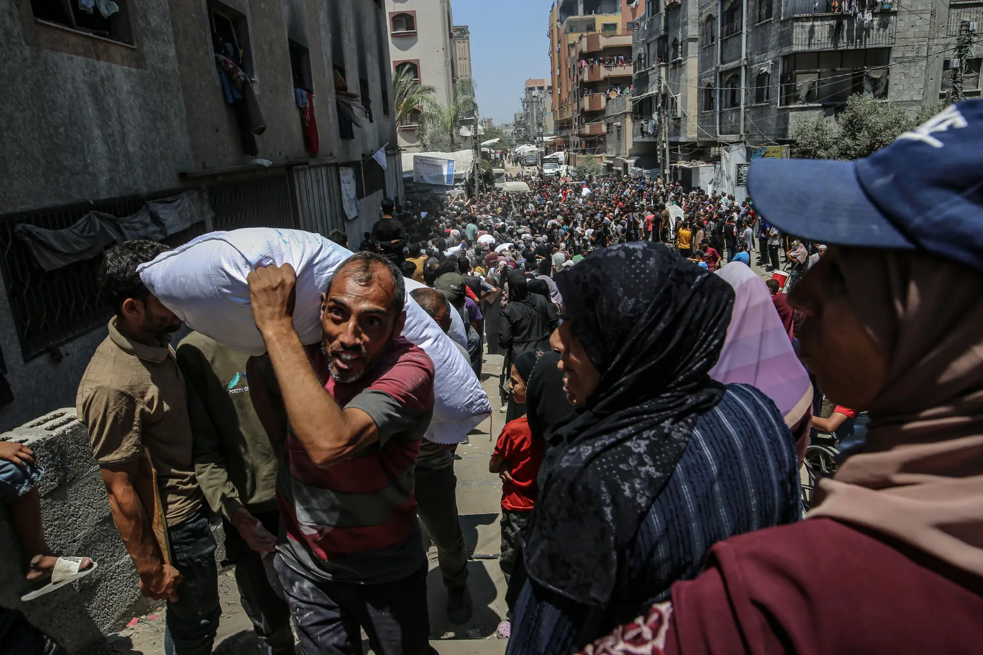 Palestinianos deslocados aguardam para receber ajuda através do Programa Alimentar Mundial (PAM) após esta ter chegado com sucesso aos armazéns da organização na cidade de Gaza