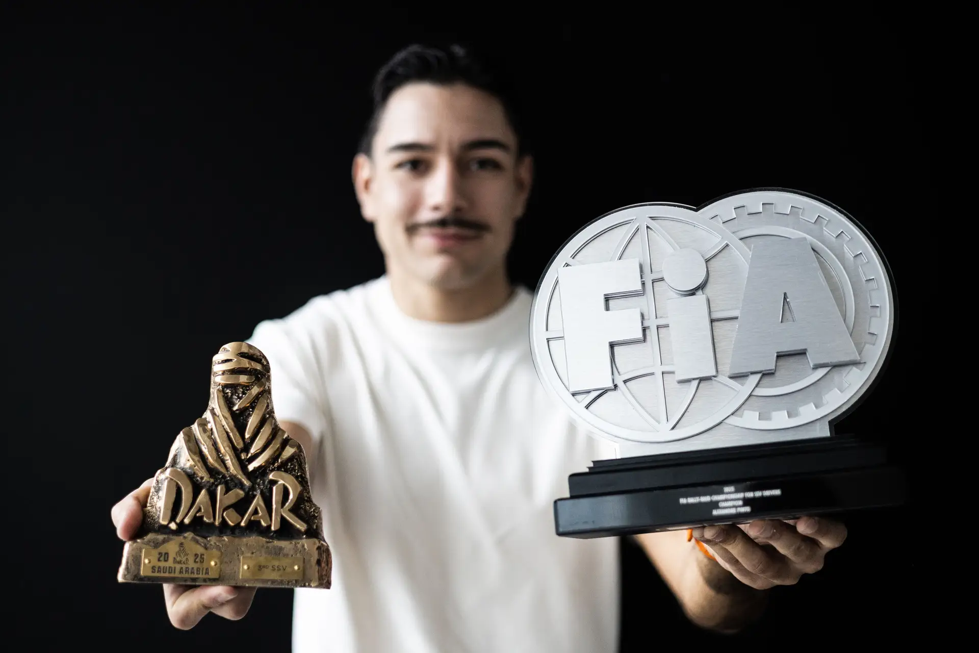 O piloto Alexandre Pinto com os troféus referente ao 3º lugar conquistado no Dakar de 2025 e ao título de campeão do mundo