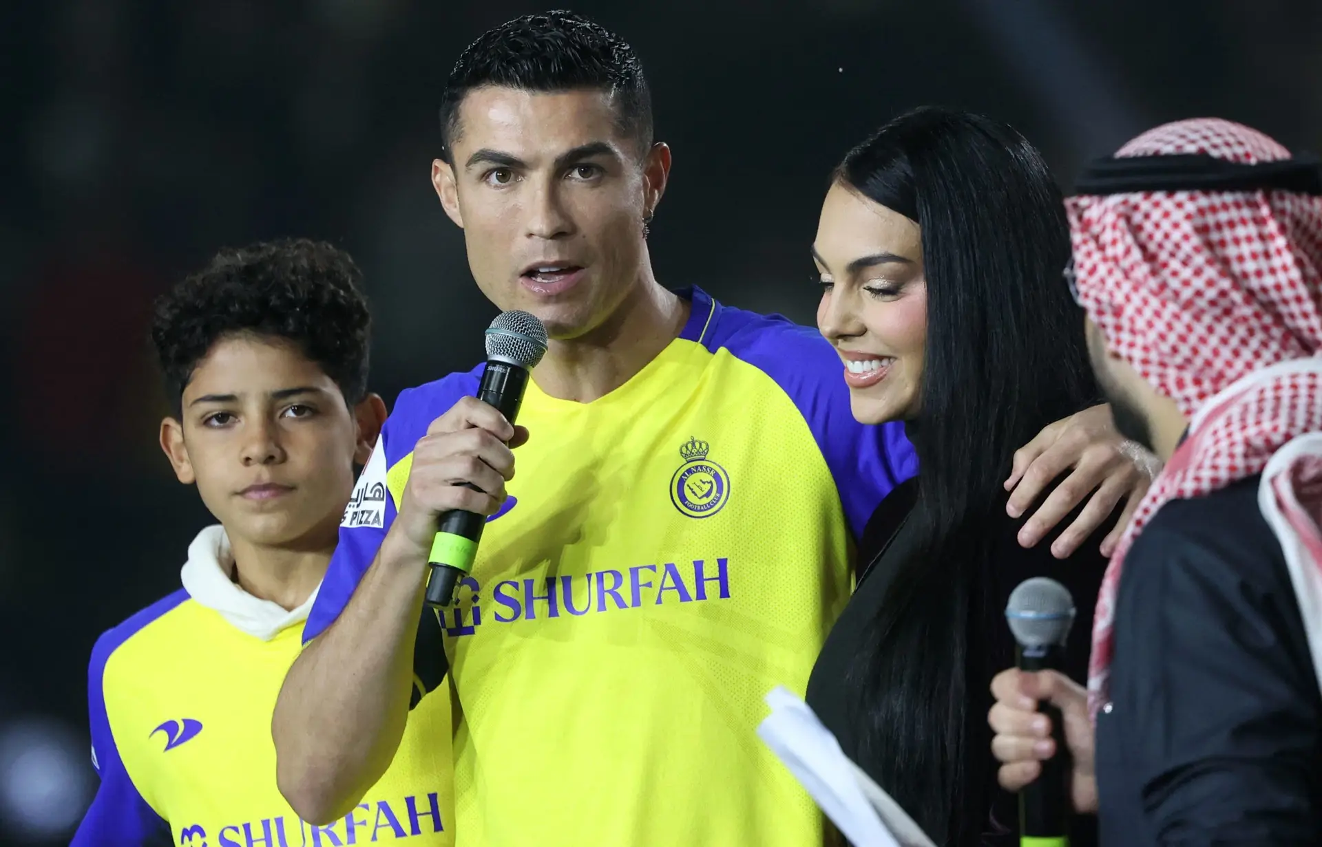 TOPSHOT – Portuguese forward Cristiano Ronaldo (C-L), accompanied by his partner Georgina Rodriguez (C-R) and his son Cristiano Ronaldo Jr, greets the crowd at the Mrsool Park Stadium in the Saudi capital Riyadh on January 3, 2023, upon his presentation as an Al-Nassr player. (Photo by FAYEZ NURELDINE / AFP) (Photo by FAYEZ NURELDINE/AFP via Getty Images)
