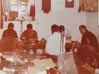 Quando era pequeno Secretário (de costas à direita) ajudava o pai na pequena fábrica familiar de sapatos de criança