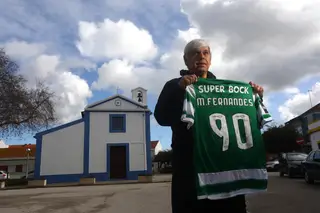 Manuel Fernandes segura a sua camisola do Sporting, junto à igreja da sua terra, Sarilhos Pequenos