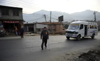 Janeiro de 2014: Bhupendra Malla, nepalês, atravessa uma estrada em Kathmandu com uma perna partida e problemas de mobilidade, danos sofridos a trabalhar nas construções no Catar para o Mundial