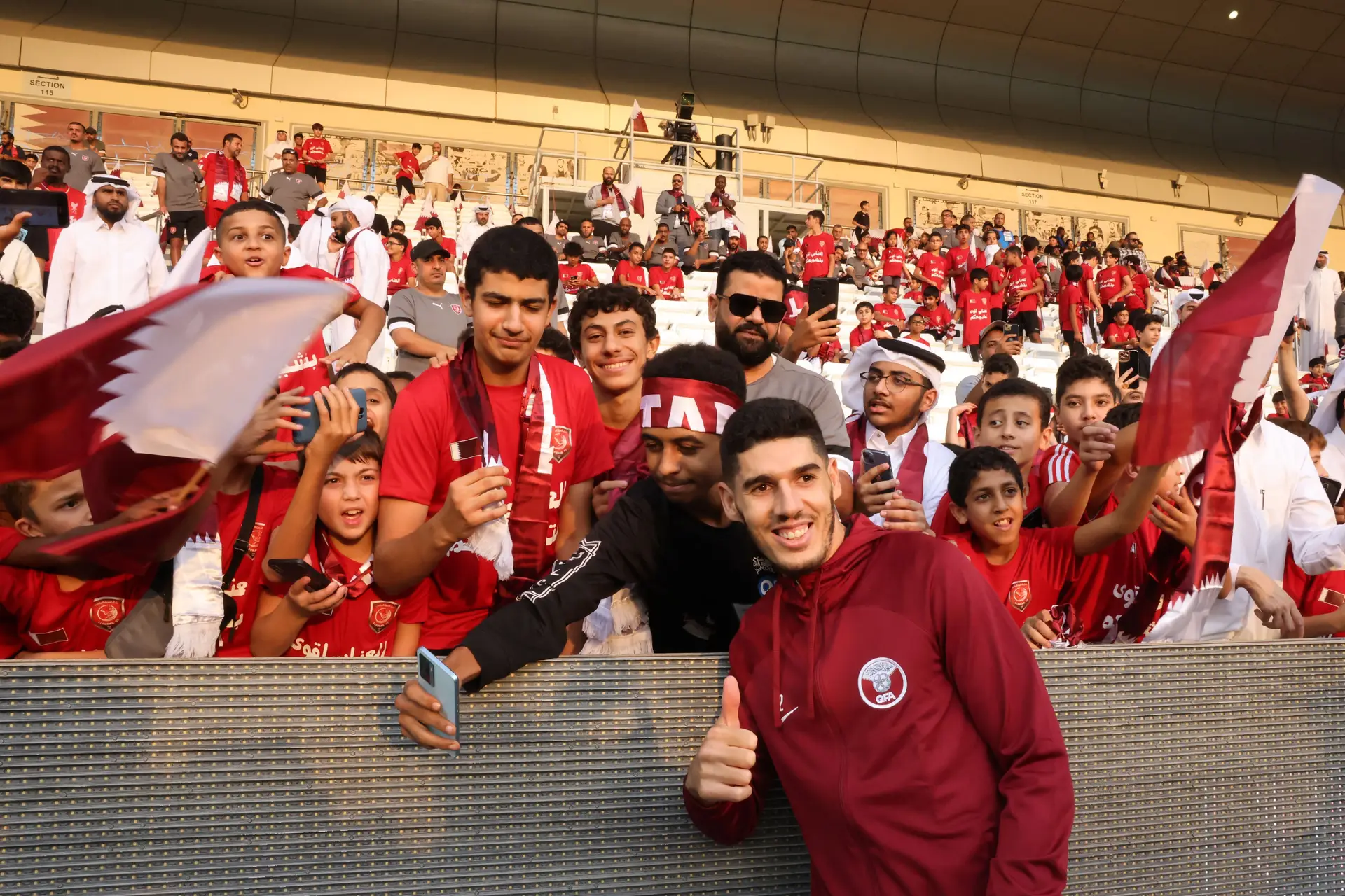 Karim Boudiaf, médio da seleção do Catar, a pousar com alguns adeptos durante um treino
