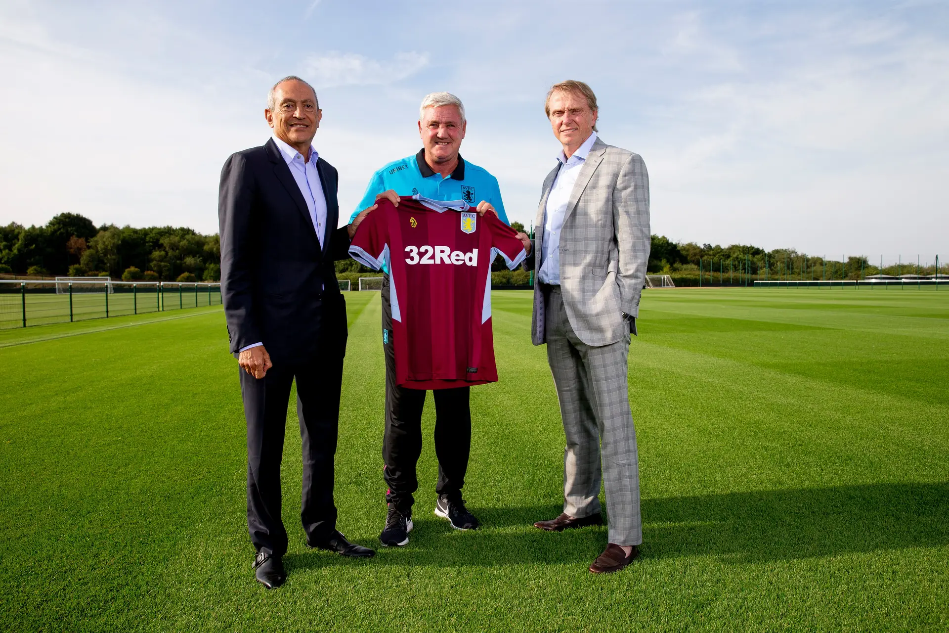 Nassef Sawiris e Wes Edens ladeiam Steve Bruce, treinador do Aston Villa em 2018, data do investimento inicial no clube inglês