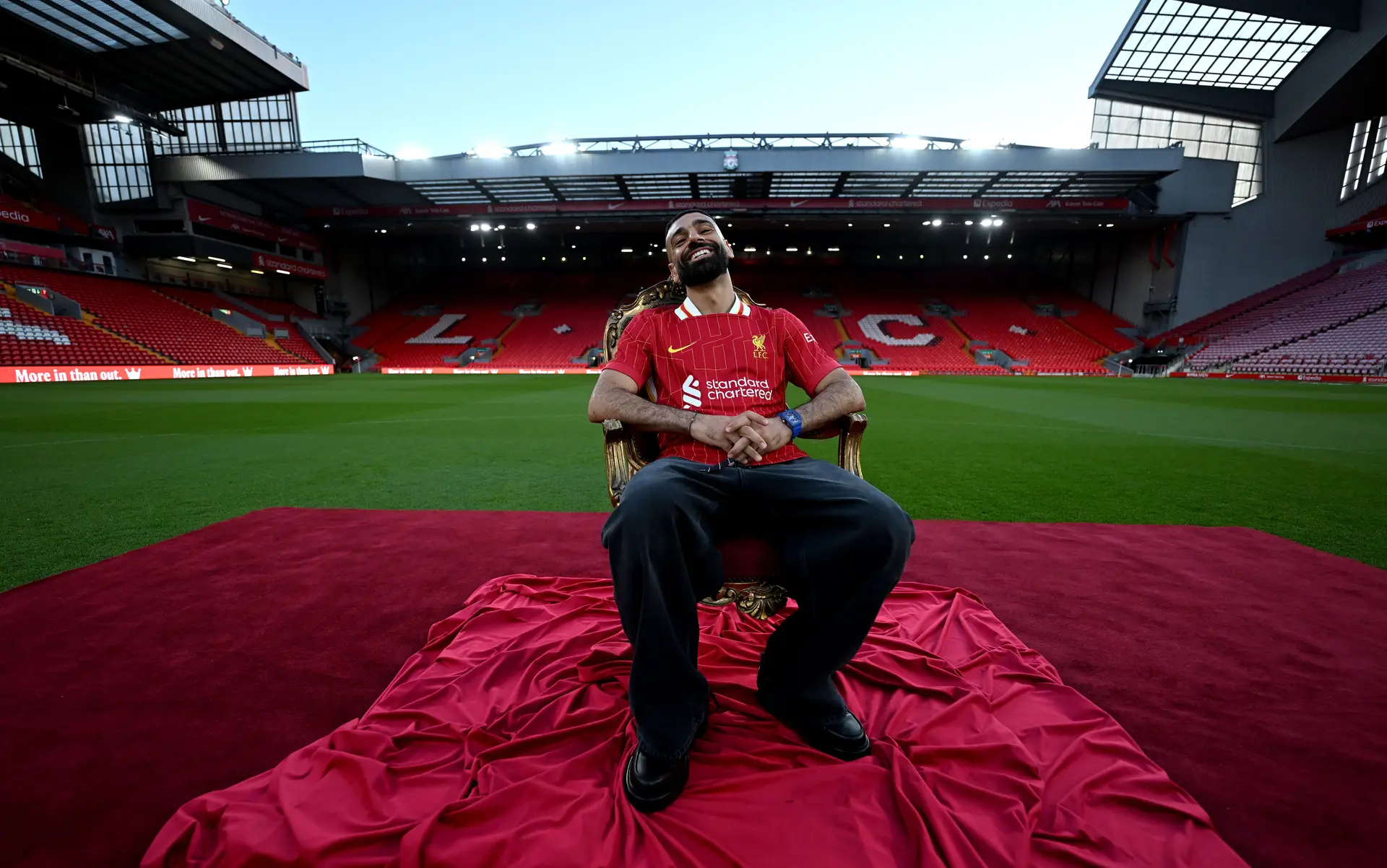 Mohamed Salah sentado num trono no centro do relvado em Anfield, no estádio do Liverpool, quando foi anunciada a renovação do seu contrato com o clube em abril de 2025