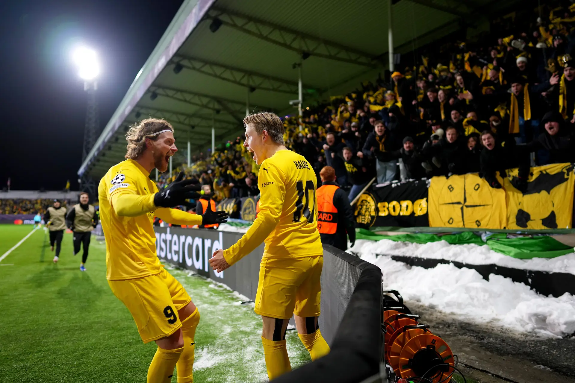 Jans Petter Hauge a celebrar com Hasper Hogh o golo que marcou ao Inter, em Bodø (com neve à beira do relvado), no jogo da 1ª mão do play-off da Liga dos Campeões