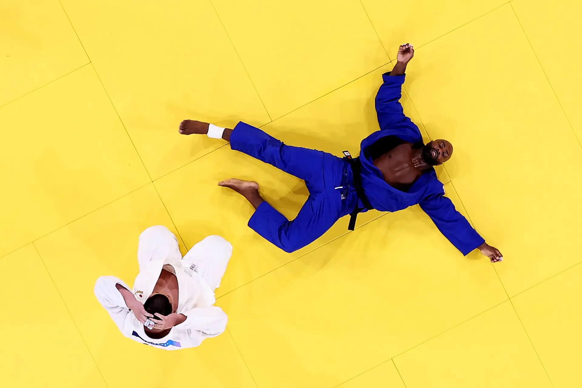 Teddy Riner estendido no tatami ao confirmar a vitória contra Tatsuru Sato na final da prova por equipas de judo nos Jogos Olímpicos de Paris, em 2024