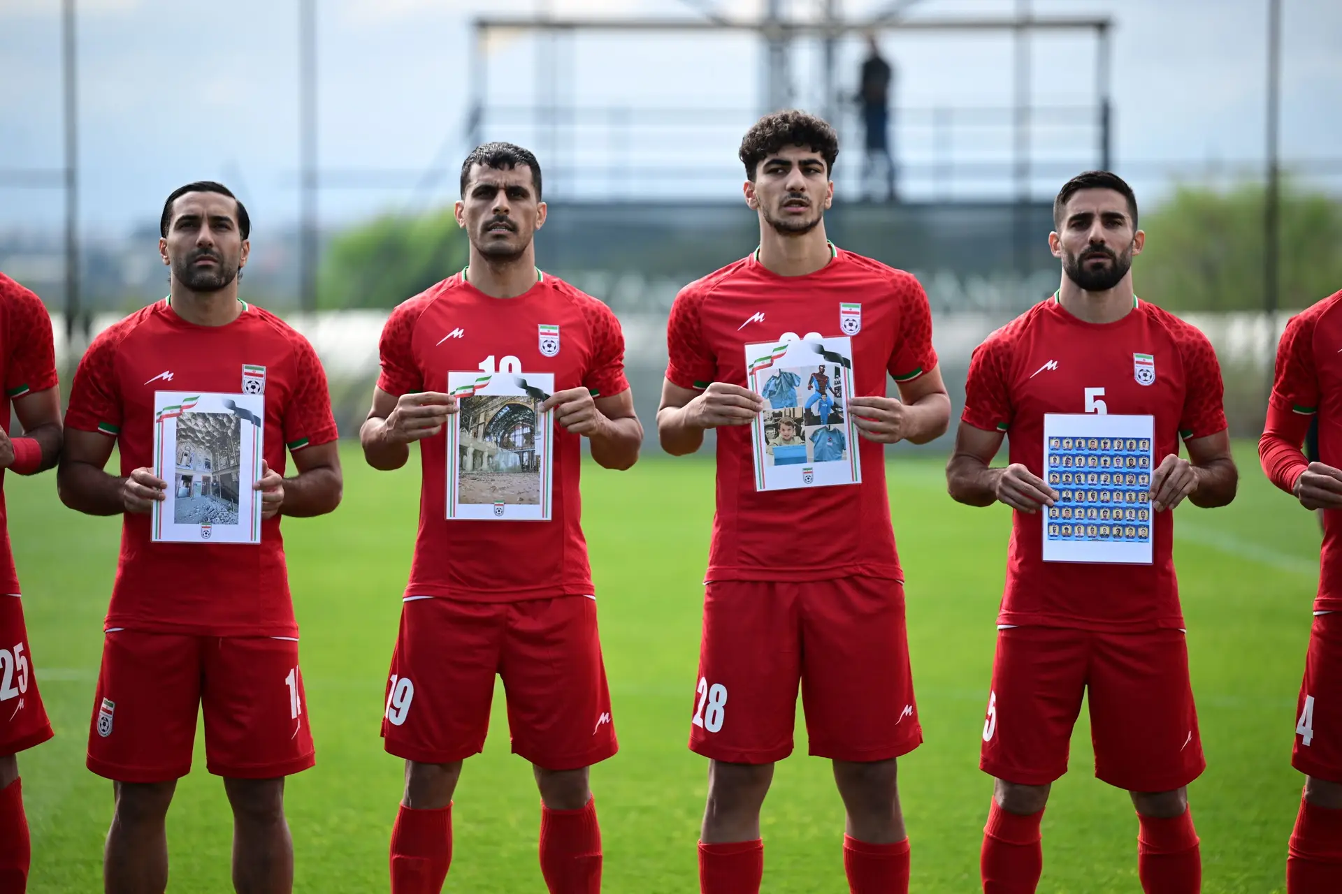 Jogadores da seleção do Irão, em março, a segurarem fotografias de crianças mortas na guerra com os EUA e Israel, antes de uma partida amigável contra a Costa Rica