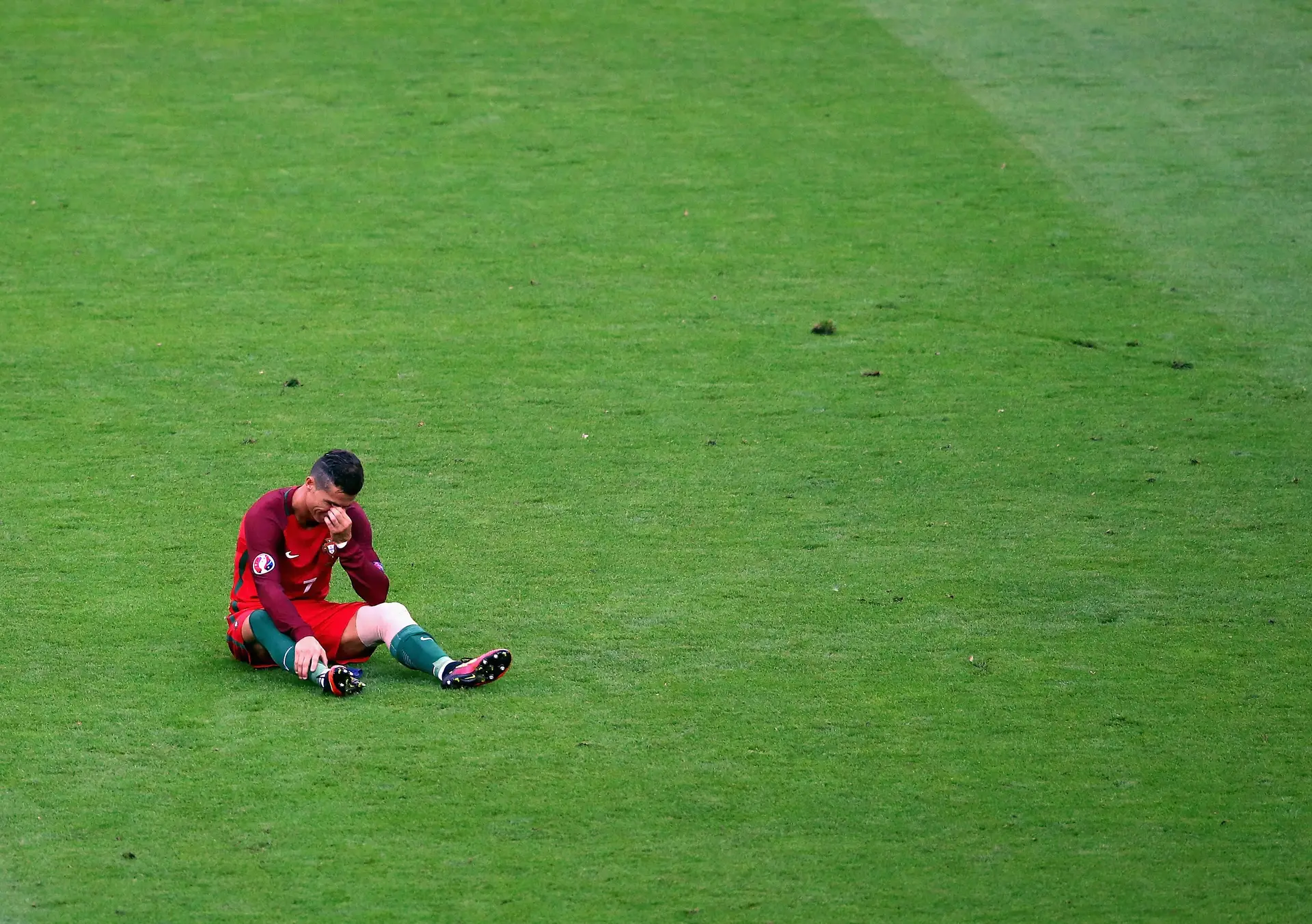 Cristiano Ronaldo sentado no relvado do Stade de France, em lágrimas, antes de ter de ser substituído por lesão ainda na primeira parte da final do Euro 2016