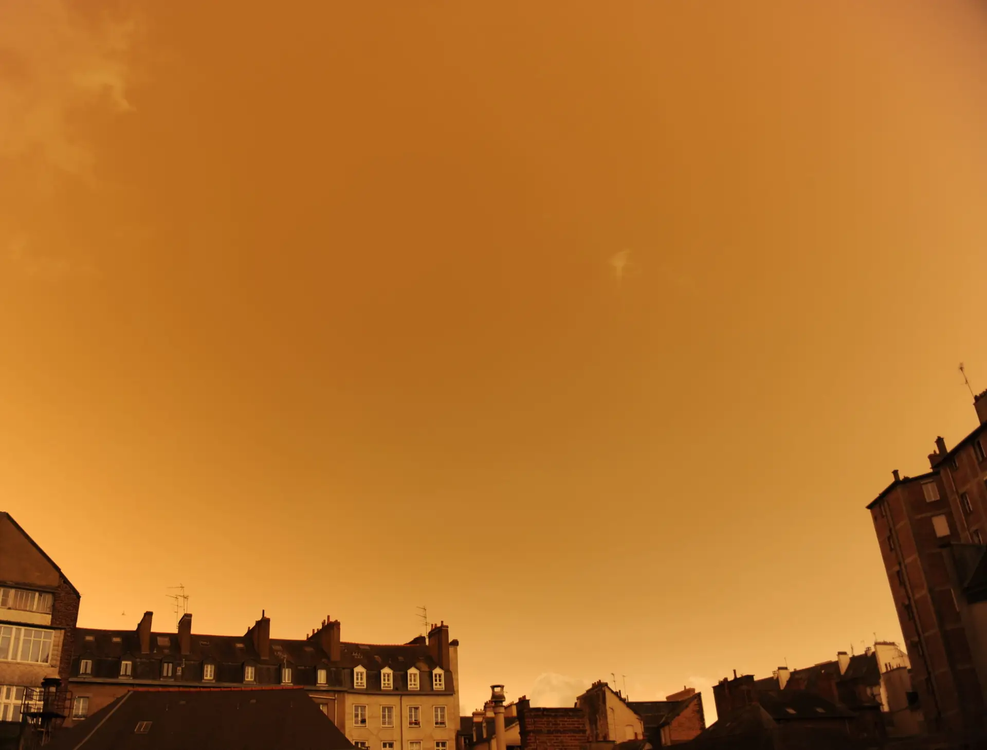 TOPSHOT – A picture taken on October 16, 2017, in central Rennes, western France, shows rooftops and the sky after it turned a yellow-ochre colour due to sand from the Sahara desert and dust from wildfires in Portugal being carried by wind from the Storm Ophelia. / AFP PHOTO / Marie DUFAY (Photo credit should read MARIE DUFAY/AFP via Getty Images)