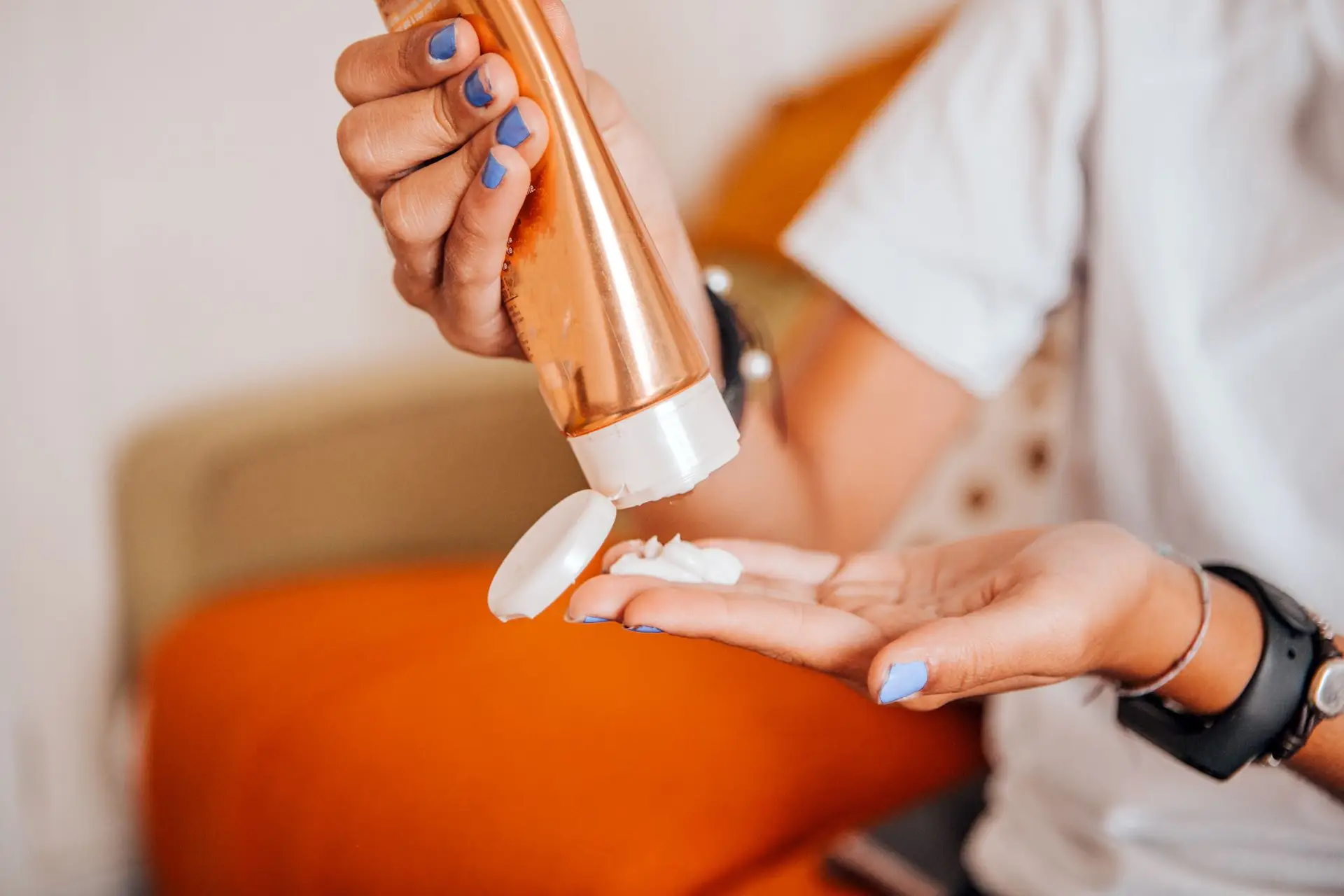 medium shot of young woman in casual clothes applying cream on arms