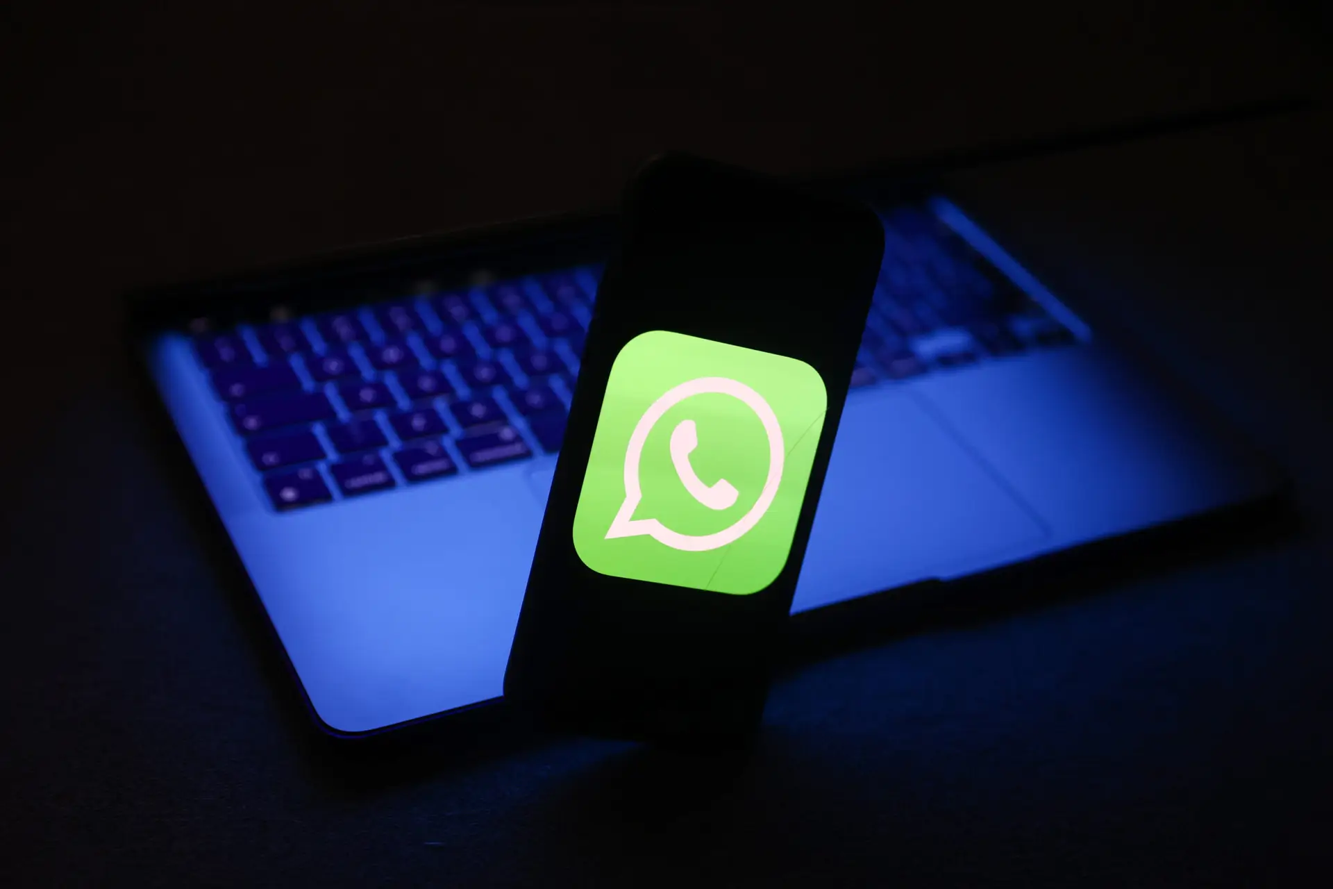 WhatsApp logo displayed on a phone screen and a laptop are seen in this illustration photo taken in Krakow, Poland on November 27, 2022. (Photo by Jakub Porzycki/NurPhoto via Getty Images)