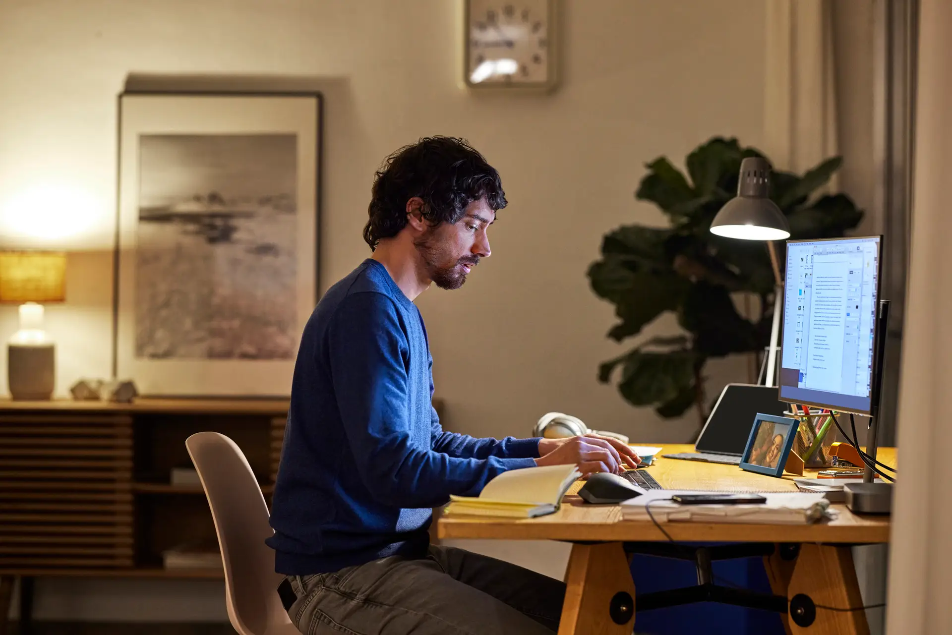 Handsome businessman using computer at home. Mid adult man is working late at office. He is sitting at table.