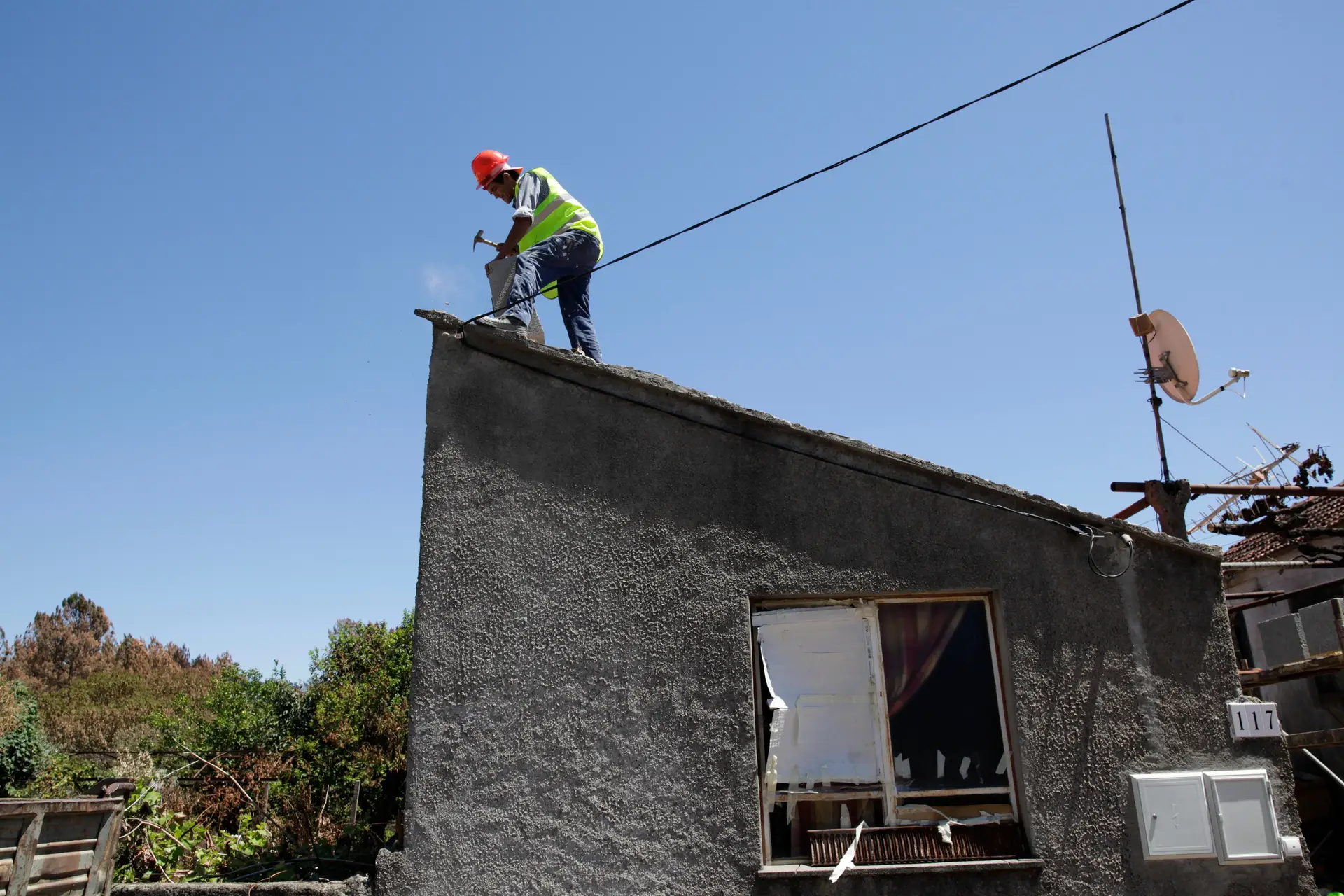 Um operário de construção civil recupera uma casa ardida, em Vila Facaia.