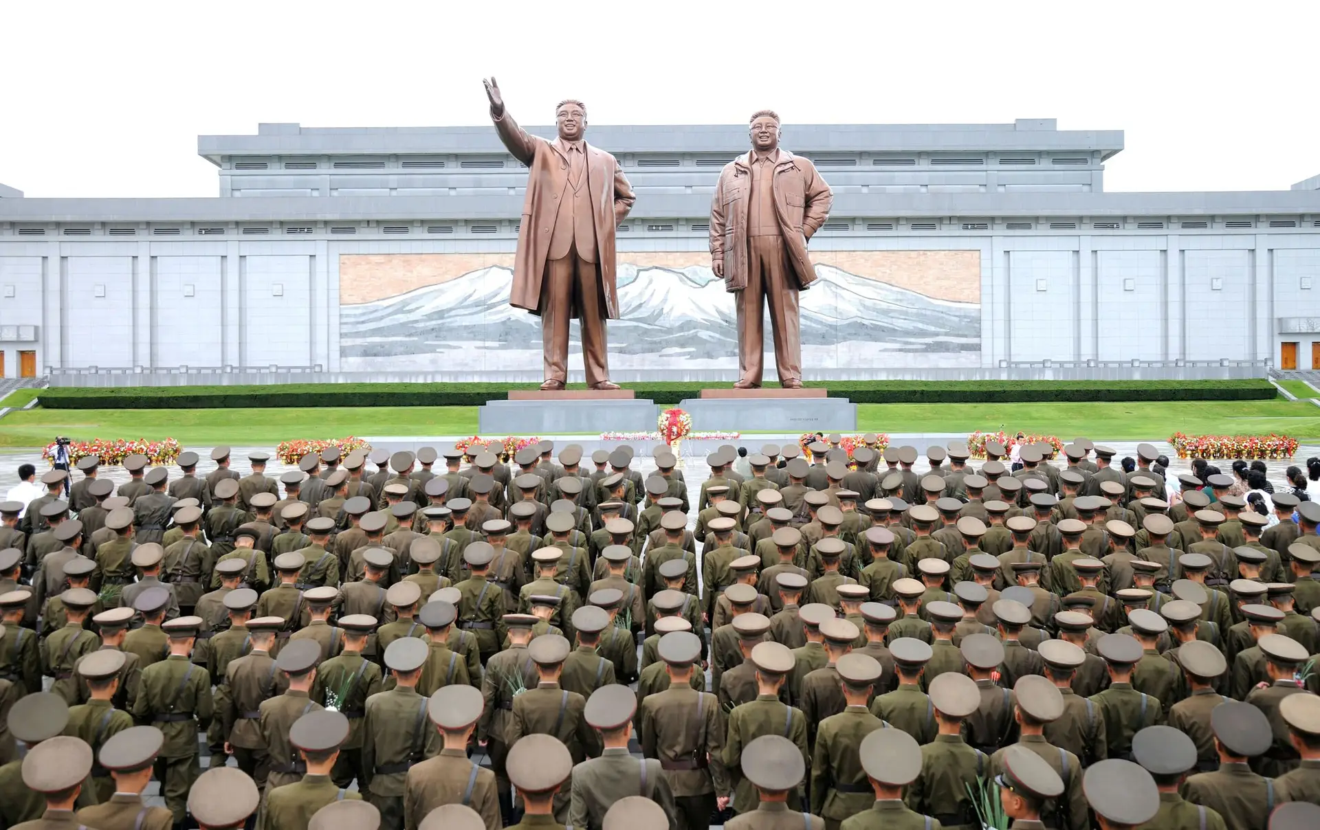 Exército da Coreia do Norte, civis, estudantes e crianças durante uma visita às estátuas de Kim II Sung e Kim Jong II, Coreia do Norte. 
