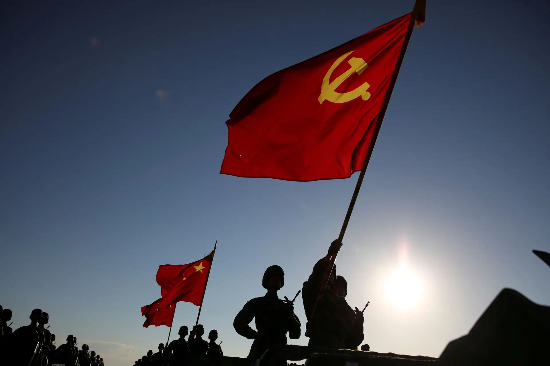 Soldados carregam bandeiras do Partido Comunista Chinês.