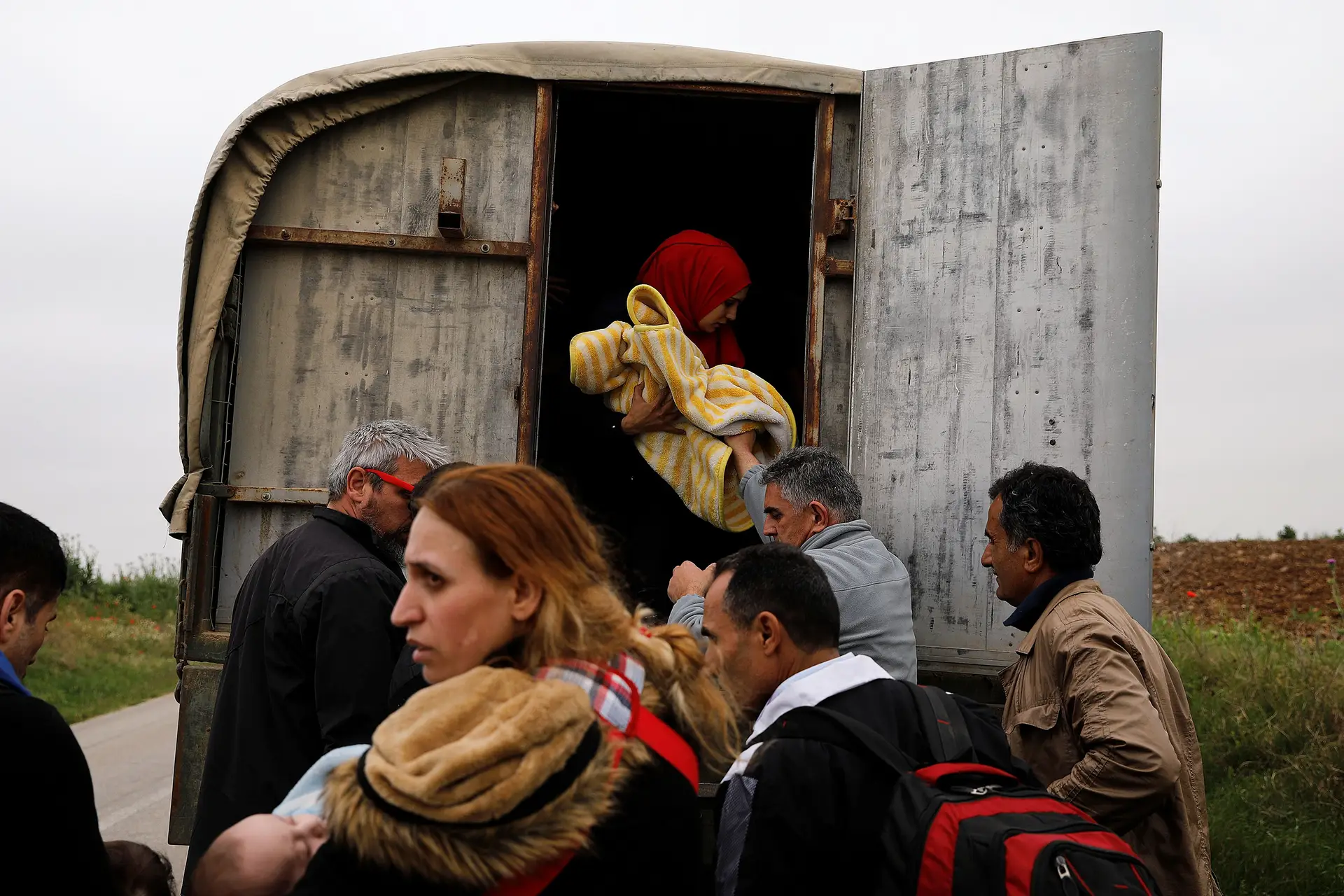 Refugiados sírios que atravessaram a fronteira entre a Grécia e a Turquia, através do rio Maritsa, entram num veículo da polícia que os irá transportar para um centro de receção.